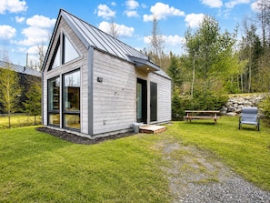 Eine kleine, eingeschossige Holzhütte mit geneigtem Dach und großen Fenstern.