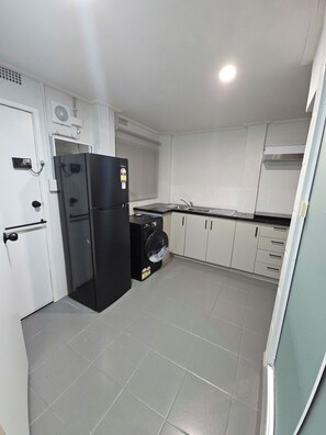 A compact kitchen with a refrigerator, washing machine, and a sink. - Private Lower‑Level 2‑Bedroom Unit – Walk to Lake Macquarie (Eleebana)