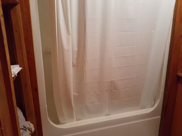 A bathroom with a shower curtain, a bathtub, and a wooden door frame.
