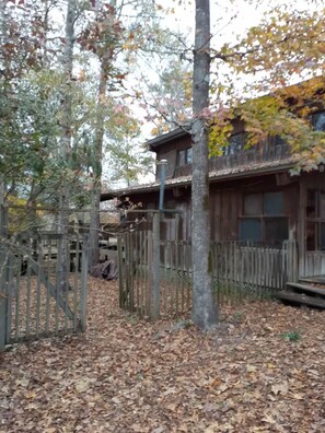 Un bâtiment rustique en bois, doté d’un porche et entouré d’arbres et d’une clôture en bois.