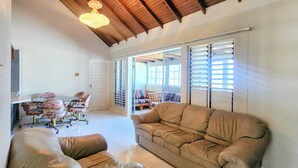 A spacious living room with a high ceiling, a dining area with floral chairs, and a large sofa. - Comfy Villa With Ocean View (St. James Parish)