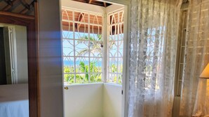 A room with a view through a window, a door, and a bed. - Comfy Villa With Ocean View (St. James Parish)