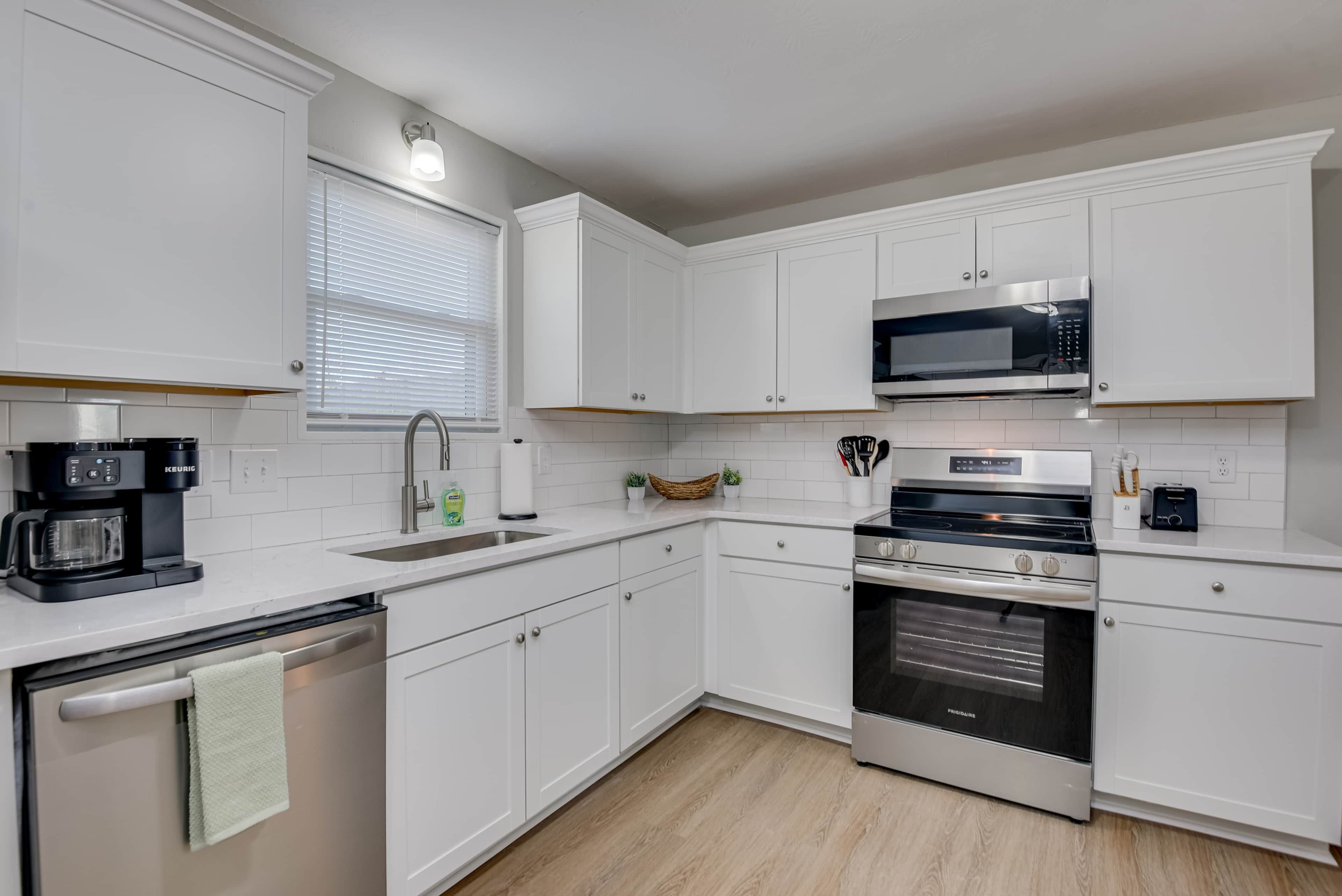 A modern kitchen with white cabinetry, a built-in microwave, a stove, and a dishwasher.