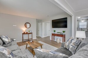 Ein Wohnzimmer mit Sofa, Couchtisch, Fernseher und einer Konsole mit Dekoration.