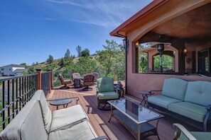 Eine Terrasse mit Gartenmöbeln, einem Glastisch und Blick auf eine hügelige Landschaft.