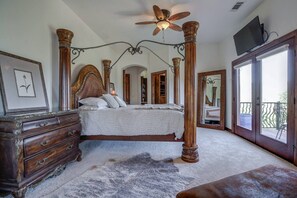 A bedroom with a four-poster bed, wooden furniture, a ceiling fan, a television, and a balcony. - Valparaiso | A West Redding Hilltop Estate (Redding)