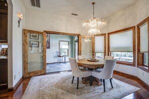 A dining area with a chandelier, round table, and chairs. - Valparaiso | A West Redding Hilltop Estate (Redding)