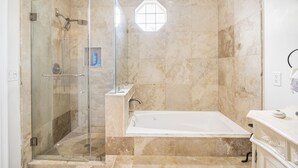 Un baño con ducha de vidrio, bañera y pared revestida de mármol.