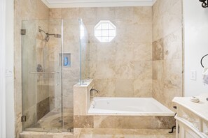 Un baño con ducha de vidrio, bañera y pared revestida de mármol.