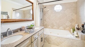 Un baño con dos lavamanos, un espejo grande, una bañera y una zona de ducha.