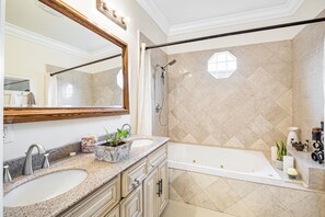 Un baño con dos lavamanos, un espejo grande, una bañera y una zona de ducha.