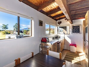 Une cuisine avec un plafond en bois, une fenêtre donnant sur un beau paysage, un grille-pain et un évier.