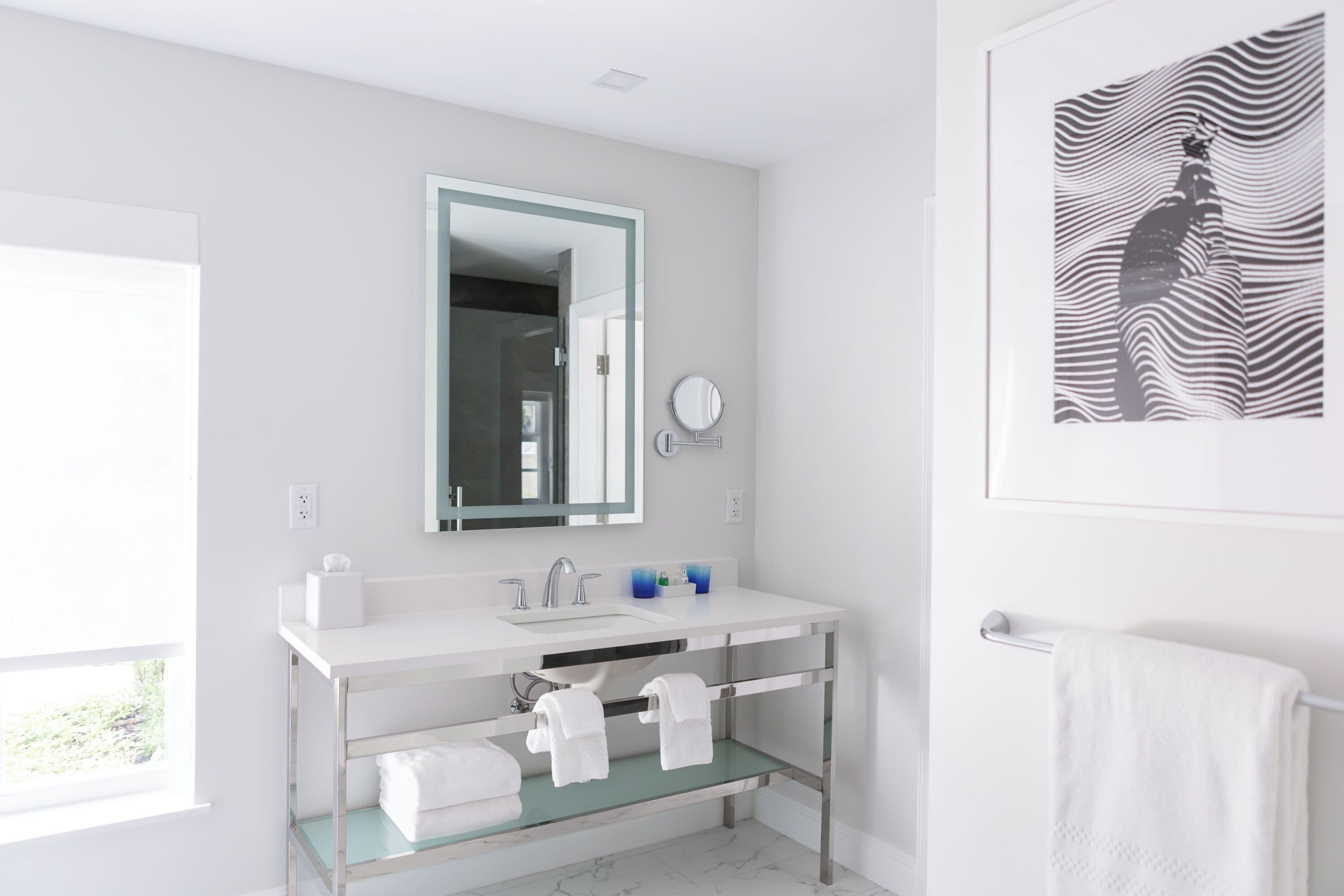 Une salle de bain moderne avec un lavabo blanc, un miroir et un porte-serviettes.