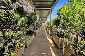 A covered walkway lined with potted plants and a building on one side. - Huge 2BD Condo With Beach Service 720 (Miami Beach)