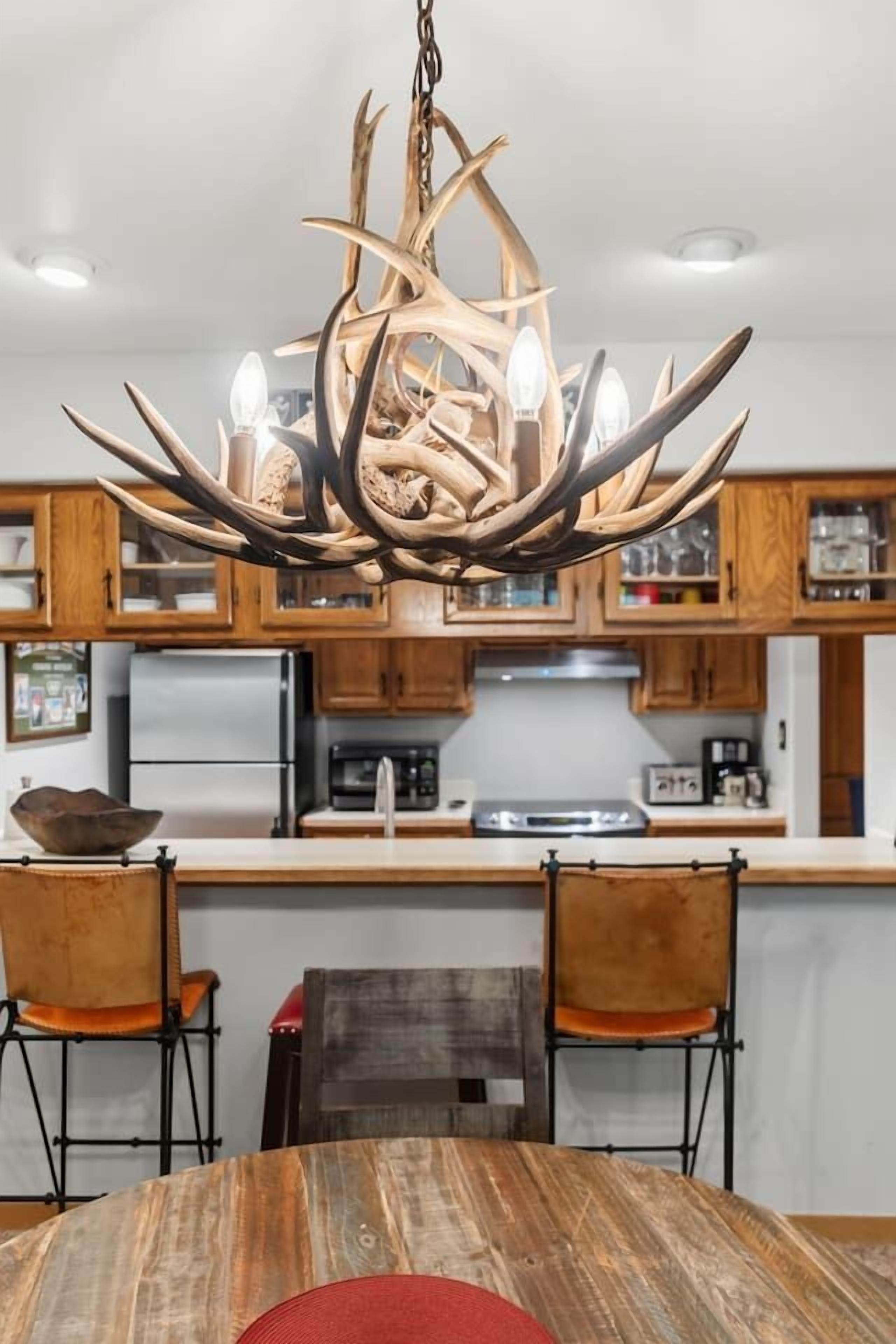 Una cocina moderna con armarios de madera, una isla central y una original lámpara de asta de ciervo.