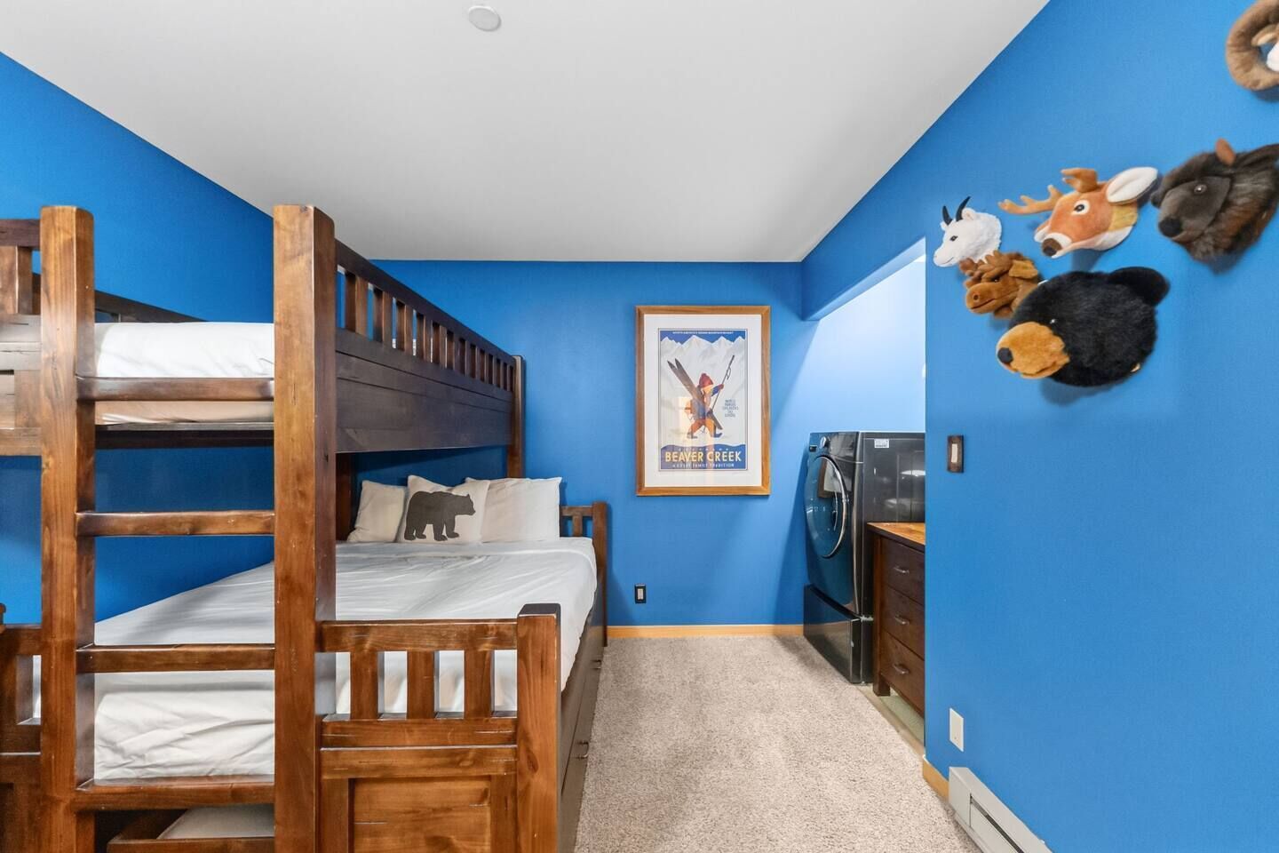 Une chambre avec un lit superposé, un poster accroché au mur et des décorations en forme d’animaux en peluche.