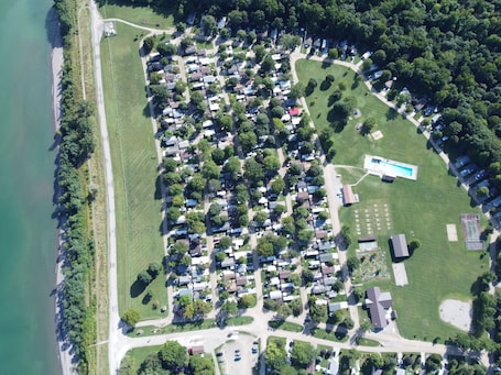 An aerial view of a residential area with houses, a swimming pool, and a tennis court.. Wildwood By The Lake! Cottage Rental in Private Park next to Lake Erie!