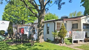 A mobile home with a backyard, a hammock, and a fire pit. - Wildwood By The Lake! Cottage Rental in Private Park next to Lake Erie! (Morpeth)