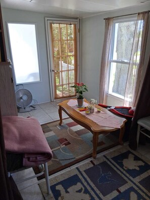 Ein Zimmer mit einem Holztisch, einem Ventilator, einer Topfpflanze und einem Stuhl.