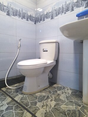 A bathroom with a toilet, a shower, and a sink.