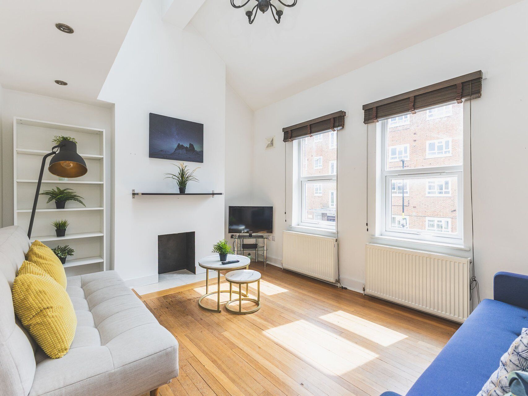 En moderne stue med sofa, sofabord, pejs, fjernsyn og store vinduer.
