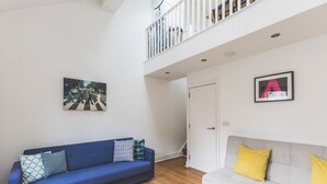 Olohuoneessa on sininen sohva, harmaa sohva, puulattia, portaat ja valkoinen ovi.