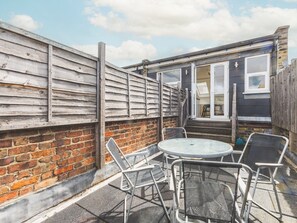A patio with a round table and chairs, a brick wall, and a wooden fence. - Bright Loft Apartment in Nine Elms (London)