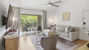 Ein modernes Wohnzimmer mit Sofa, Sessel und Deckenventilator.