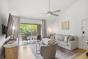 Una sala de estar moderna con sofá, sillón y ventilador de techo.