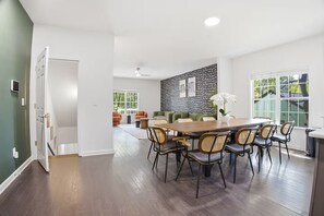 Ett rymligt matområde med ett träbord och stolar, en grön soffa och en vägg med ett mönster.