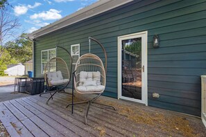 A house with a porch, two hanging chairs, a door, and a window.