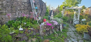 Ein Garten mit einem Kiesweg, Kübelpflanzen, einer Schwan-Dekoration und einem Fahrrad.