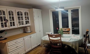 Una cucina con mobili bianchi, un tavolo da pranzo con tovaglia e una finestra vista panoramica.