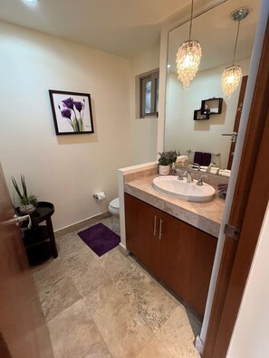 A bathroom with a sink, mirror, chandelier, and a framed picture on the wall. - Beautiful apartment in the Zona Romantica, just two blocks from the beach! (Emiliano Zapata neighborhood, Puerto Vallarta)