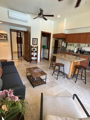 A modern kitchen with a central island, a dining area with a sofa and coffee table, and a ceiling fan. - Beautiful apartment in the Zona Romantica, just two blocks from the beach! (Emiliano Zapata neighborhood, Puerto Vallarta)