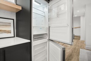 A modern kitchen with a built-in refrigerator, wooden shelves, and a white countertop. - Stylish Queen Studio Apartment with Fast Wi-Fi & Parking (Ottawa)