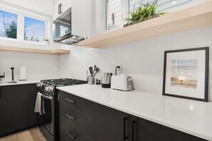 A modern kitchen with a stove, toaster, and a framed picture on the counter. - Stylish Queen Studio Apartment with Fast Wi-Fi & Parking (Ottawa)