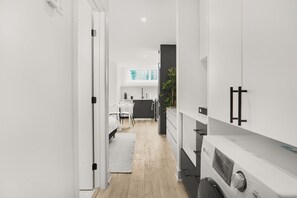A narrow hallway with a dining area, kitchen, and a washing machine. - Stylish Queen Studio Apartment with Fast Wi-Fi & Parking (Ottawa)