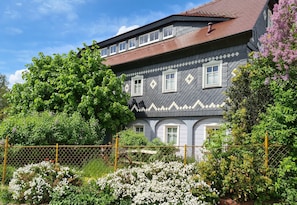 A traditional house with a grey facade, multiple windows, and a red roof. - Experience monument protection: Stylish half-timbered attic with a feel-good climate (Kottmar OT Obercunnersdorf)