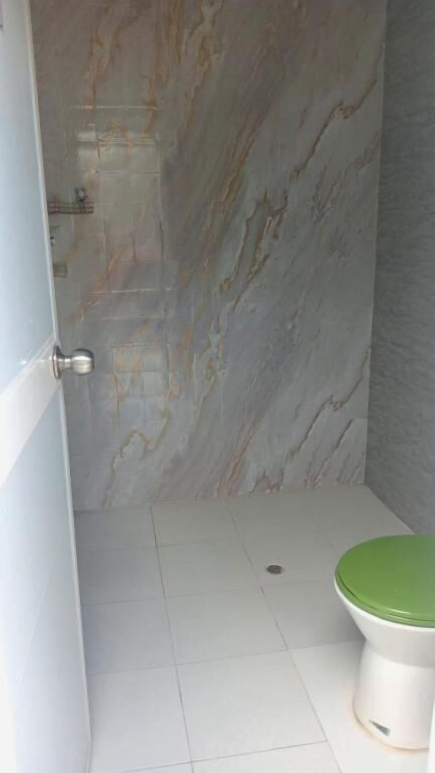 Une salle de bain avec des toilettes, des murs en marbre et un sol carrelé.
