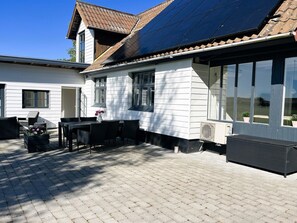 Una casa con patio, pannelli solari e una zona salotto esterna coperta.