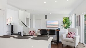 Ein modernes Wohnzimmer mit einem weißen Sofa, einem Esstisch und einem großen Fenster mit Blick.