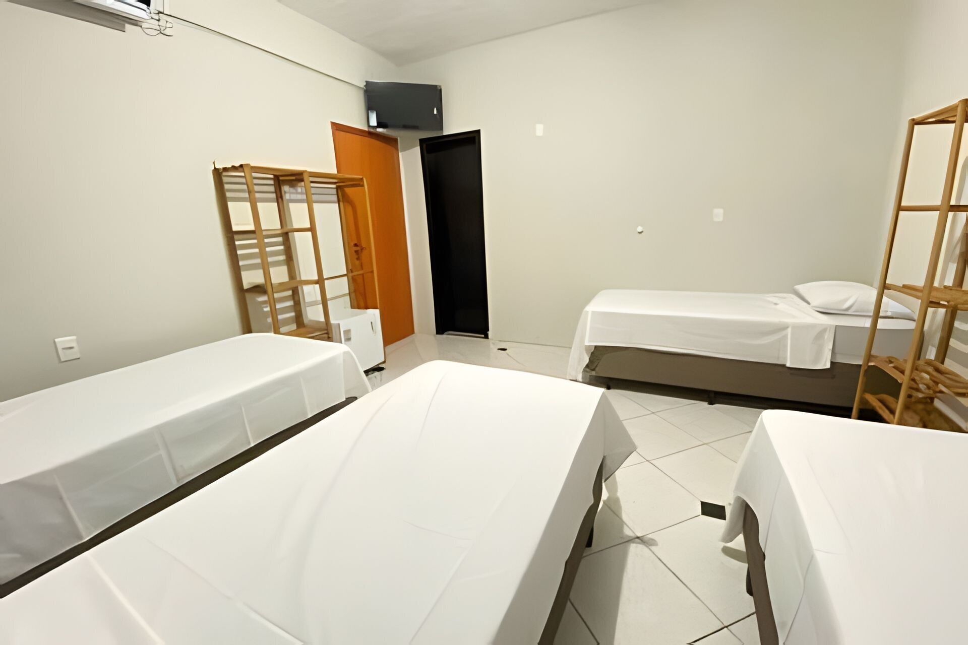 A hotel room with two beds, a wooden ladder, a small table, and a door.