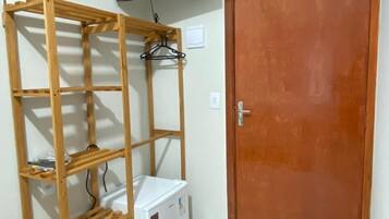 A room with a wooden shelving unit, a white refrigerator, a door, and a mounted television.