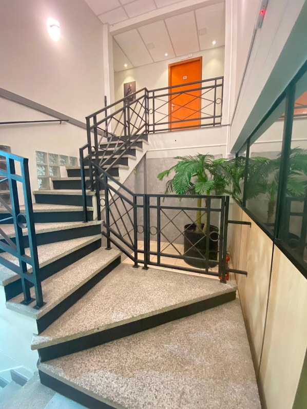 A staircase with a metal railing, a potted plant, and a door in the background.
