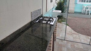A kitchen with a gas stove, a countertop, and a glass door leading to an outdoor area. - Casa praia da pinheira Piscina (Palhoça)