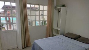 A room with a bed, a window, a door, and a wardrobe. - Casa praia da pinheira Piscina (Palhoça)