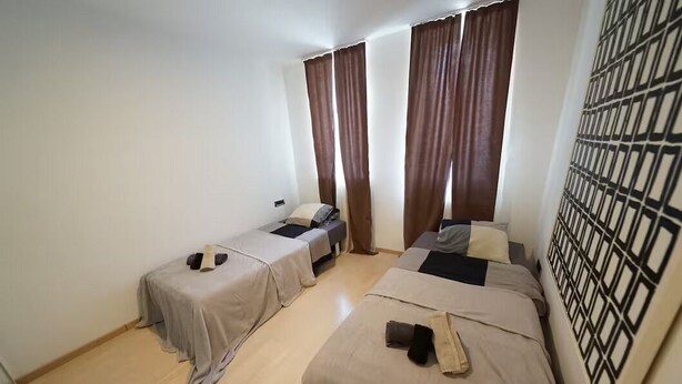 Une chambre avec deux lits, une fenêtre avec des rideaux et un mur décoré de motifs.