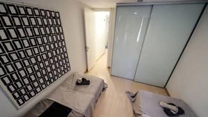 Una stanza moderna e accogliente con due letti, un armadio e un pannello decorativo.