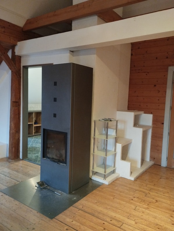 A modern interior with a fireplace, wooden beams, and a white shelving unit.